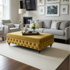 Living room with a yellow ottoman, gray sofa, and framed pictures on the wall.